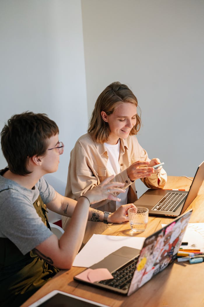 brand-03 Two young professionals brainstorming ideas at a collaborative workspace with laptops and notes.