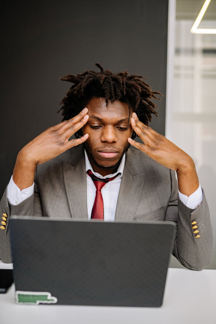 creative-03 A business professional experiencing stress at work while using a laptop in an office.